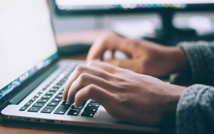 Person typing on a laptop keyboard, representing internet hacks that make life online easier.