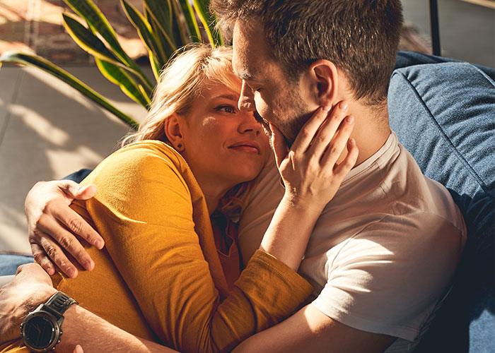 Couple sharing an intimate moment on a couch, illustrating a cheat code discovered in marriage that actually works.