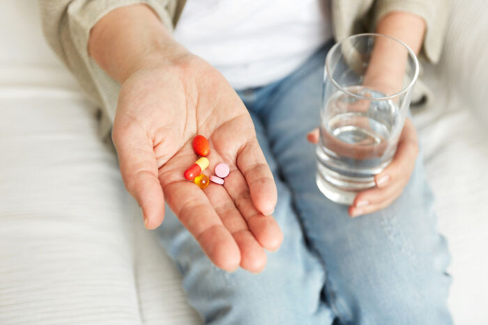 Person holding colorful pills and a glass of water, highlighting a source of fear at night.