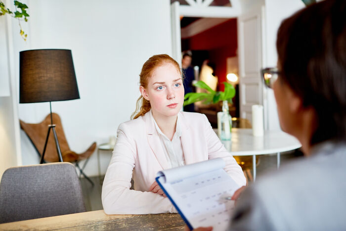 Young woman attentively answering during a job interview, facing an interviewer asking ridiculous questions.