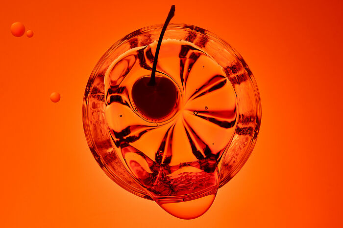 Abstract top-view photo of a cocktail with a cherry, resembling a flower, shortlisted for 2025 World Food Photography Awards.