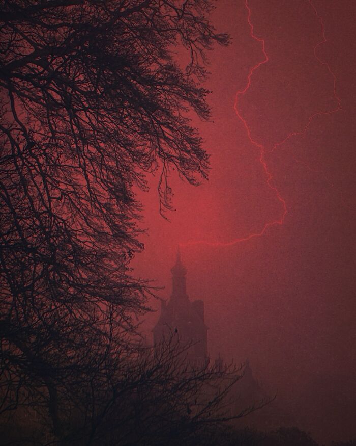 Dark escapism photography by Nona Limmen featuring a silhouetted castle under a stormy red sky.