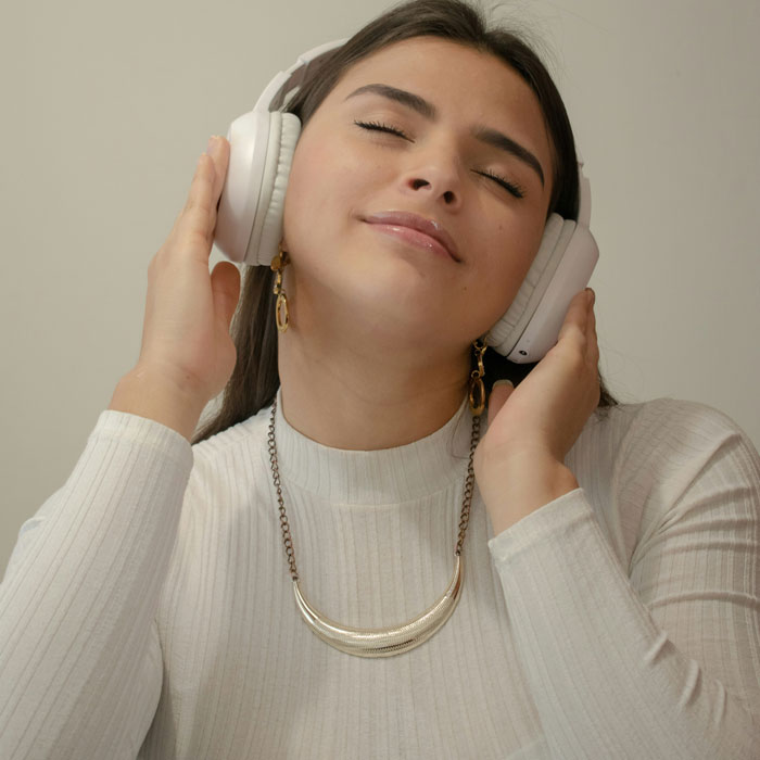 Woman enjoying music on headphones, showcasing internet hacks for a relaxed online experience.