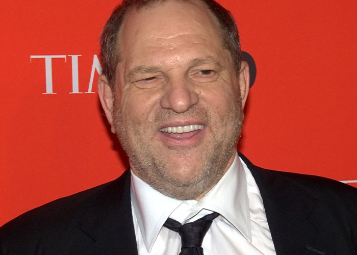 Man in a suit smiling against a red backdrop at a formal event, related to wild rumors proven true.