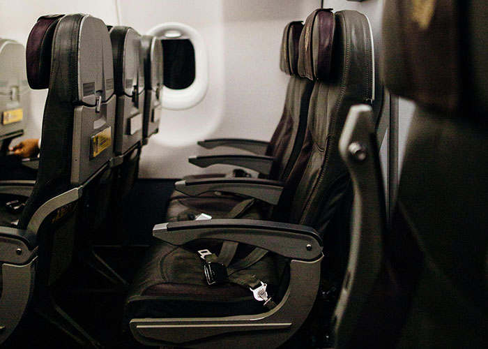 Empty airplane seats with seatbelts, viewed from the aisle, evoking unexpected plane behavior.