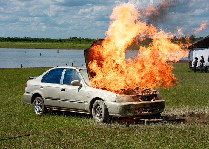 Car engulfed in flames in an open field, showcasing unrealistic movie effects.