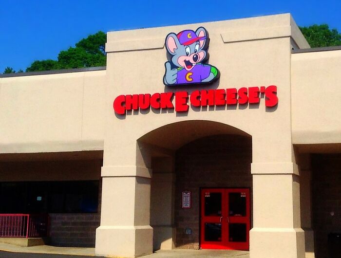 Chuck E. Cheese's entrance on a sunny day, featuring the iconic mouse logo above the red doors.