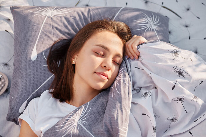 Woman peacefully sleeping under dandelion-patterned sheets, illustrating relationship insights.