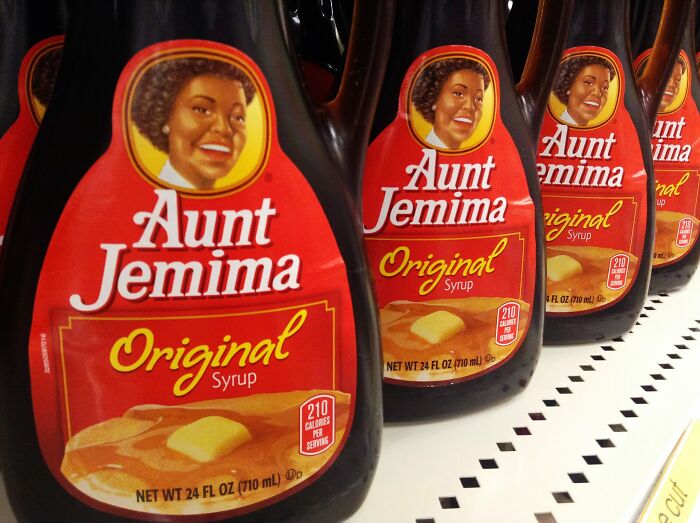 Syrup bottles on a shelf, featuring Aunt Jemima branding.