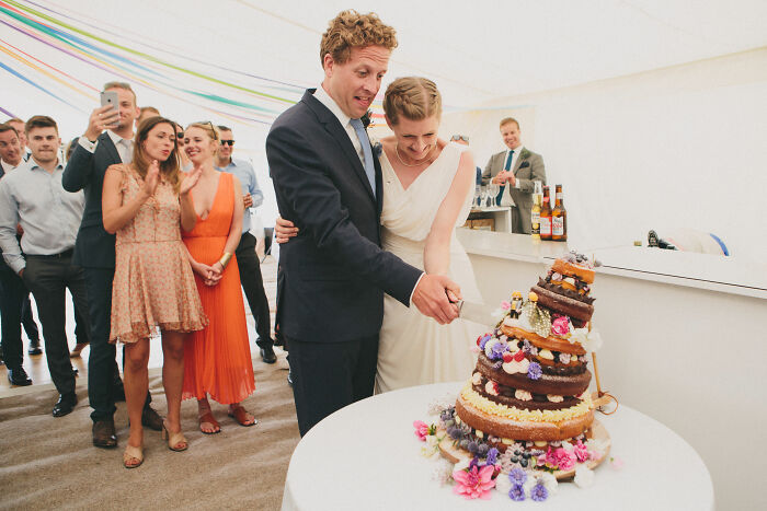 Couple cutting cake at an event, surrounded by guests, celebrating World Food Photography Awards 2025 shortlist.