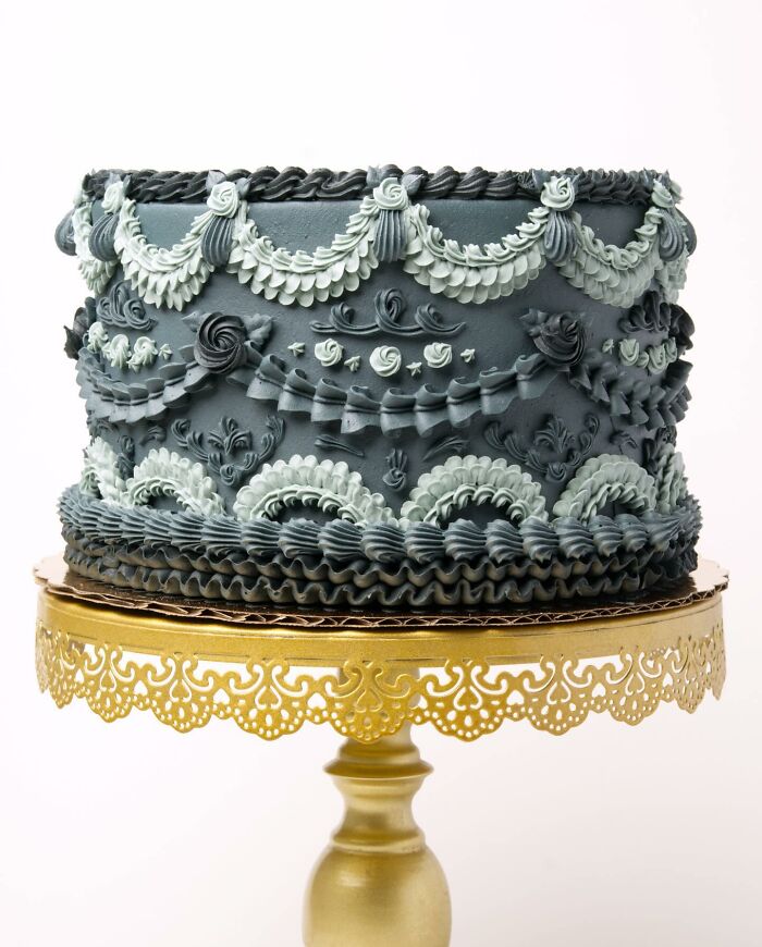 Intricately decorated vegan cake with ornate icing on a gold stand.
