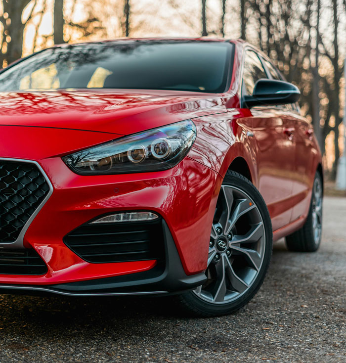 Red car parked on a wooded path, reflecting the theme of being too close to parents with its polished, close-knit vibe.