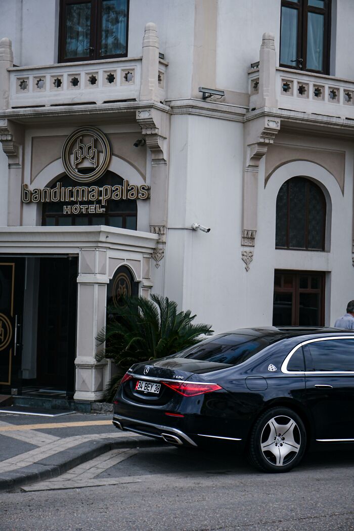 Luxury black car parked outside an ornate hotel entrance, illustrating things that look awesome in movies but are terrible in real life.