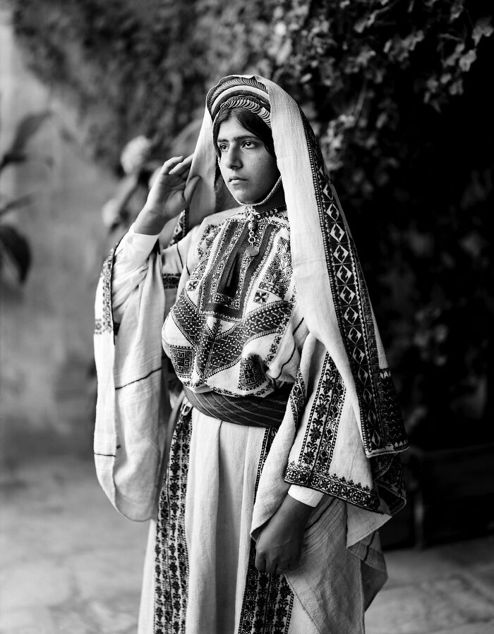 Young woman in traditional embroidered attire captured in a rare photograph restored from glass negatives.