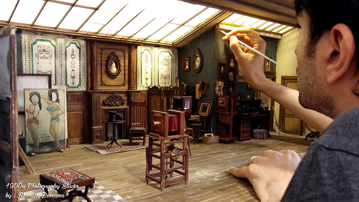 Person painting an intricate miniature 1900s photography studio, highlighting incredible detail and craftsmanship.