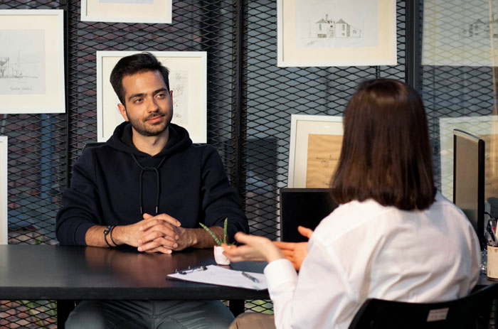 Two individuals in a job interview setting, one taking notes while the other listens attentively.