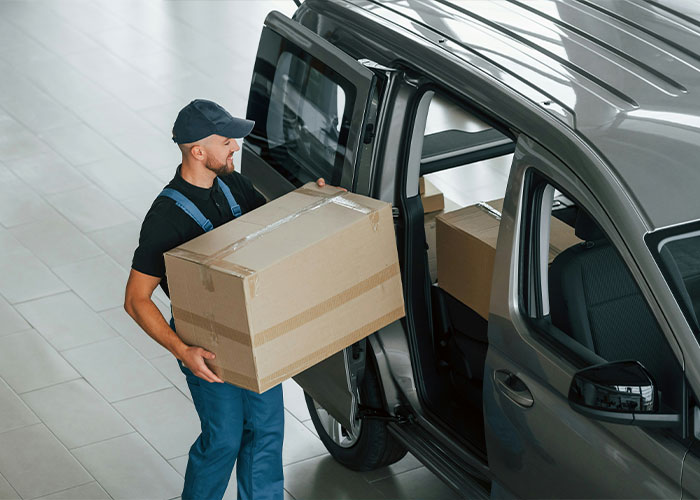 Man carrying boxes into a black van, possibly moving items related to HOA issues.