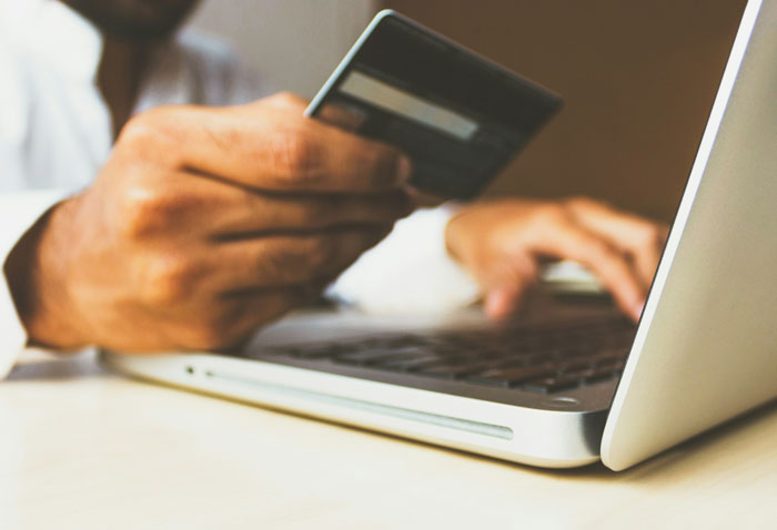 Person holding a credit card in front of a laptop, illustrating internet hacks for easier online transactions.