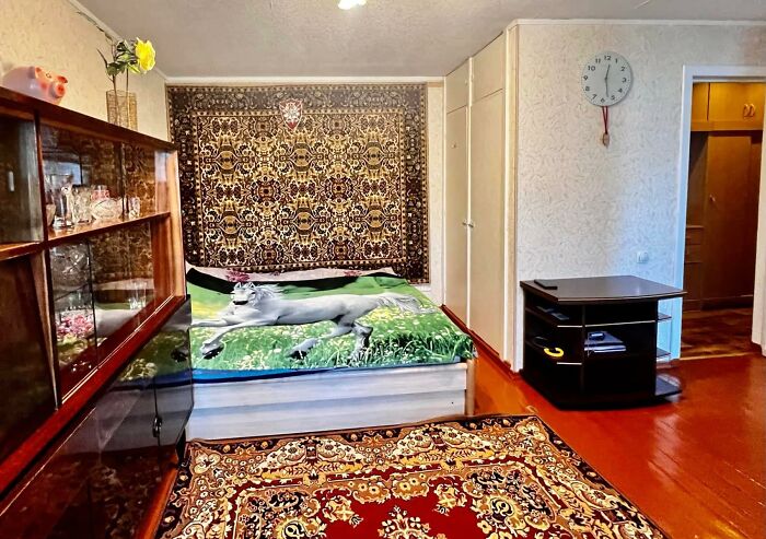 Cozy bedroom with vintage furniture, animal print bedding, ornate rugs, and patterned wall tapestry in wild real estate property.