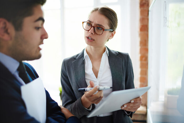 Two professionals in a job interview discussing questions, with a focus on ridiculous interview questions shared.