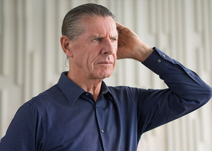 Man in a blue shirt, looking thoughtful, represents challenges with HOA decisions.