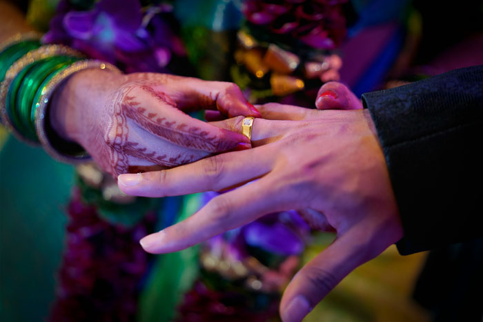 Hands exchanging rings with henna designs, symbolizing closeness and relationships.