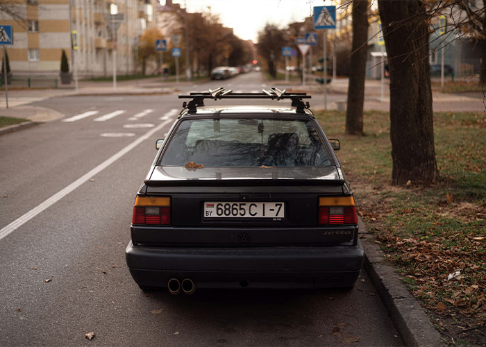 A black car parked on a quiet street, highlighting unrealistic movie scenarios.