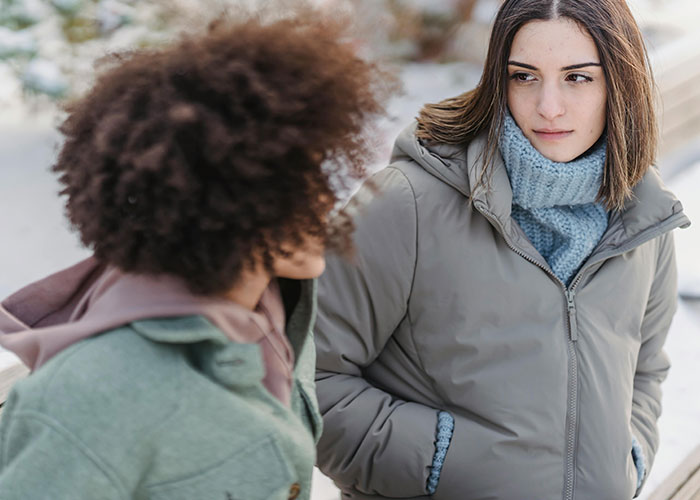 Two women having a serious conversation outdoors, depicting emotions related to heartbroken people revealing cheating signs.