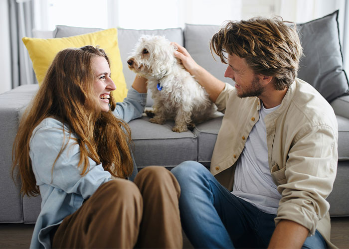 Happy couple sitting on the floor with their dog, sharing a joyful moment that feels like a marriage cheat code.