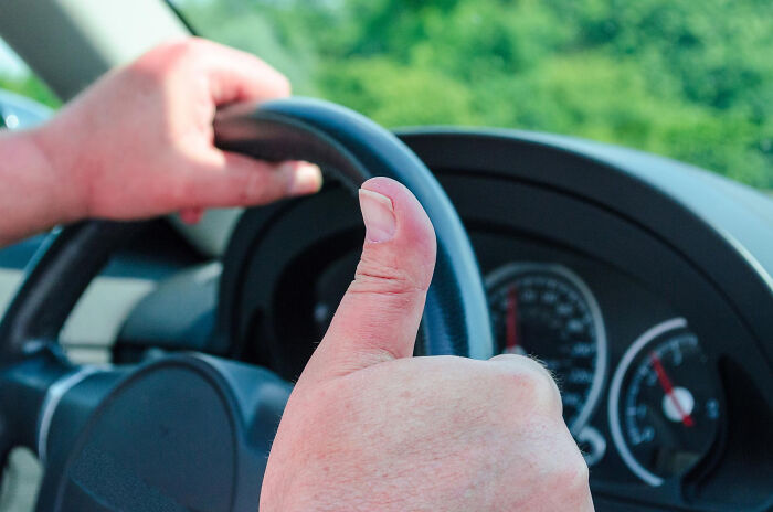 Close-up of a person driving a car and giving a thumbs up, capturing a super normal thing in the country.