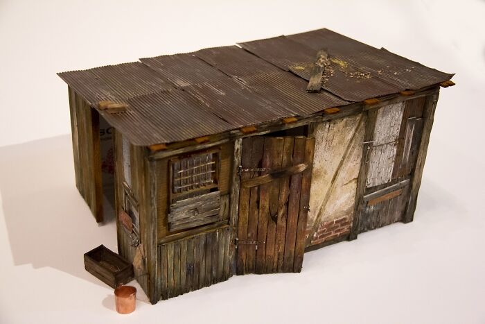 Miniature shack with weathered wood and tin roof, reflecting a rustic, secret world with intricate details.
