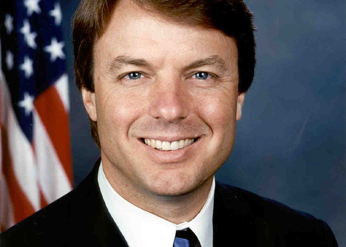 Smiling man in a suit with a flag backdrop related to wild rumors that were true.