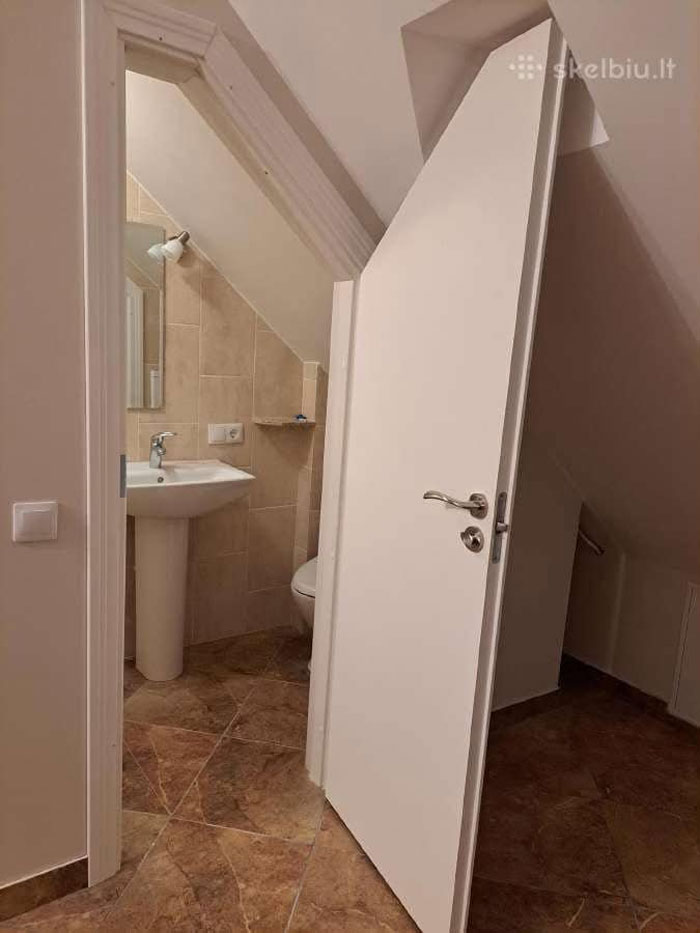 Small bathroom with angled ceiling and unique door design in one of the wildest real estate properties for sale.