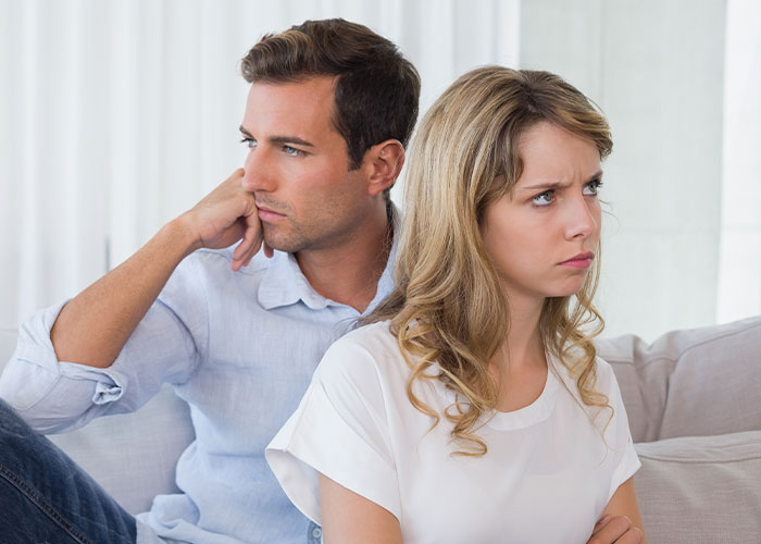 A man and woman sitting apart on a couch looking upset, illustrating challenges in marriage and relationships.