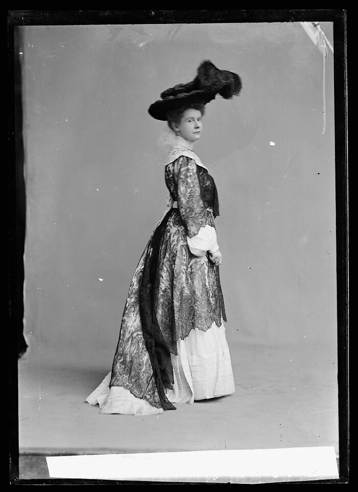 Woman in vintage dress and large hat posing in rare historical photograph rescued from glass negatives.