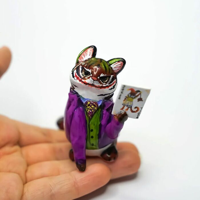 Adorable pocket-sized animal figurine by Vallavica, featuring a charming cat in a colorful outfit, held in hand.