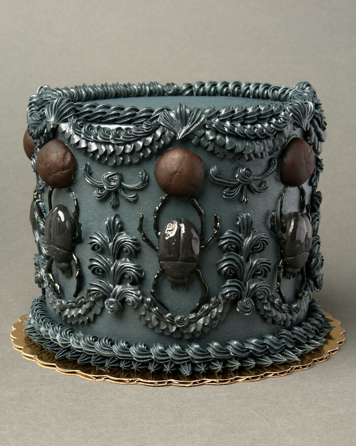 A visually stunning cake decorated with detailed bug designs and ornate patterns in dark tones.