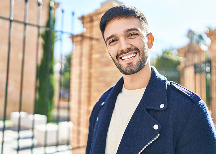 Smiling man in a blue jacket outdoors, representing HOA challenges stories.