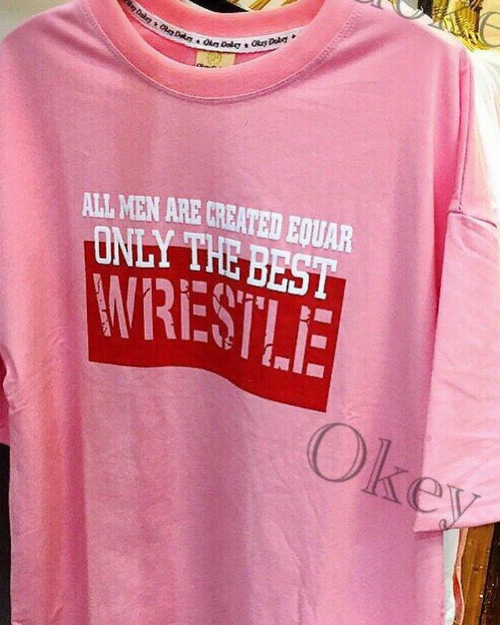 Pink T-shirt with humorous grammar error saying, "ALL MEN ARE CREATED EQUAR ONLY THE BEST WRESTLE."