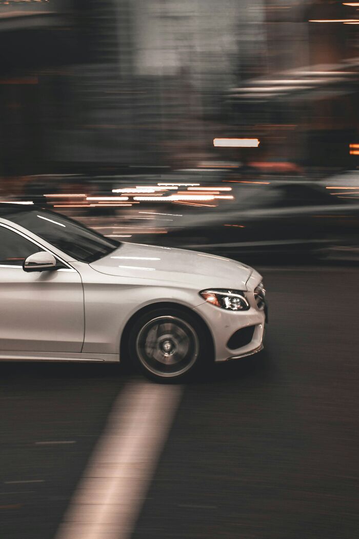 White car speeding through city streets at night, illustrating things that look awesome in movies but are terrible in real life.