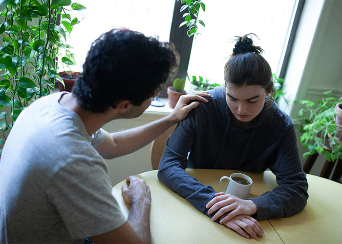 Man comforting woman during a serious conversation at a table, illustrating relationship cheat code discovered in marriage.