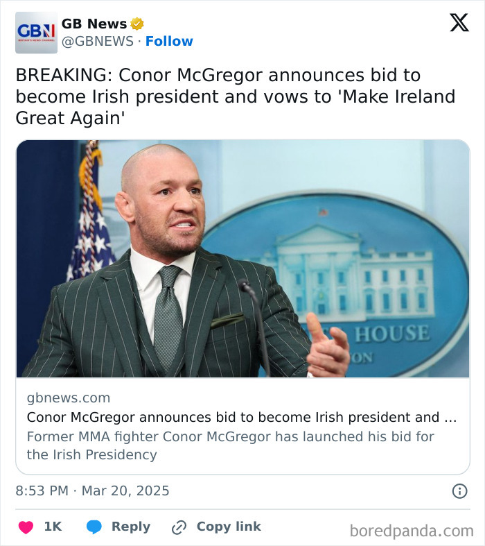 Bald man in a green striped suit speaking at a podium, addressing the media.