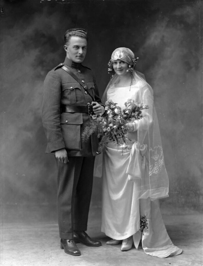 Vintage wedding photo of a couple; bride in a veil with bouquet, groom in uniform, timeless love captured.