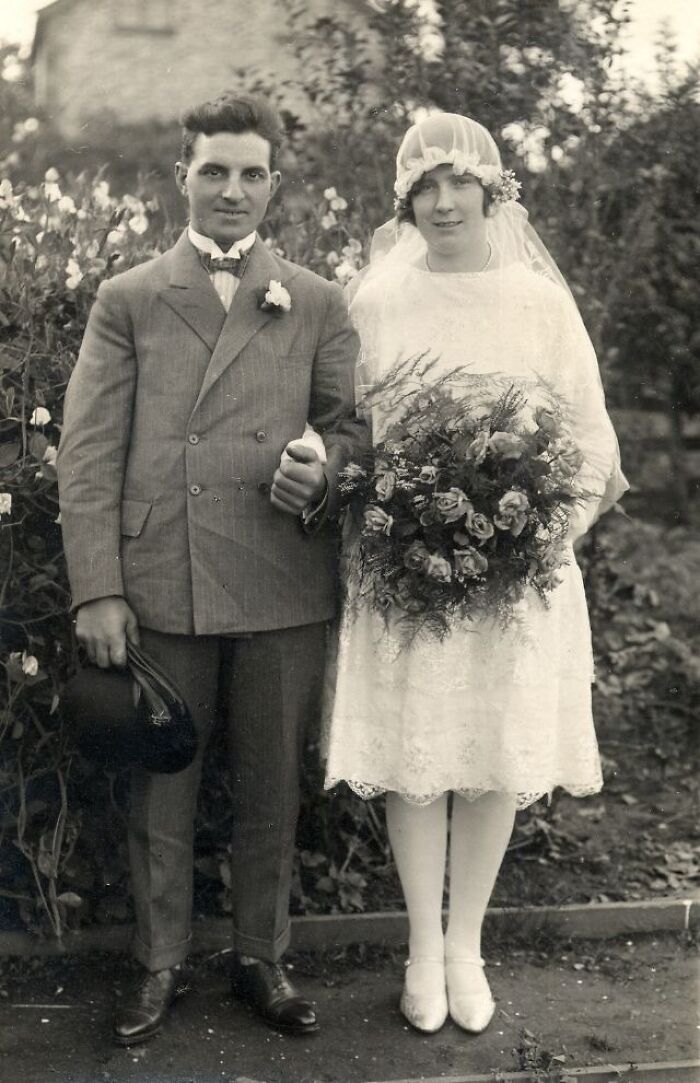 Vintage wedding photo of a couple in classic attire, with the bride holding a large bouquet.
