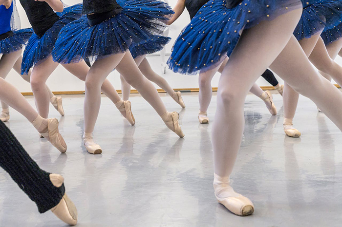 Dancers in blue tutus practicing ballet, related to a mom's concern over a dance teacher's unusual invitation.