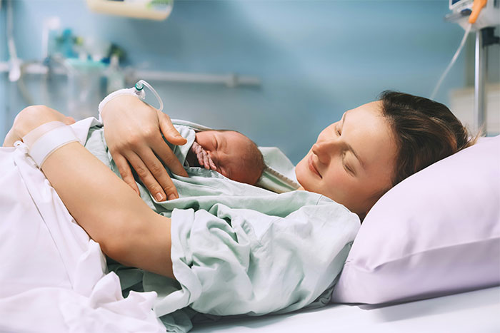 Mother peacefully holding her newborn baby in a hospital bed, conveying a sense of calm and warmth.