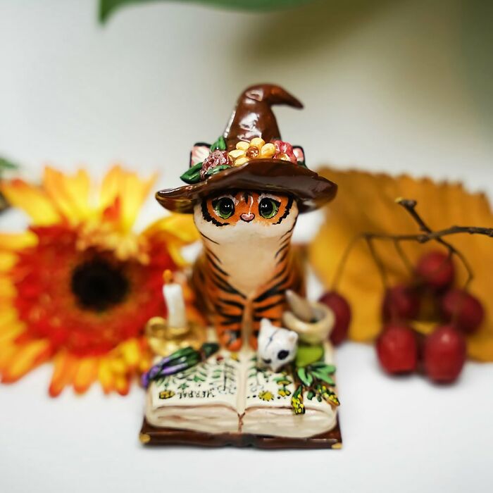 Adorable pocket-sized animal figurine of a cat in a hat, surrounded by fall-themed decor.