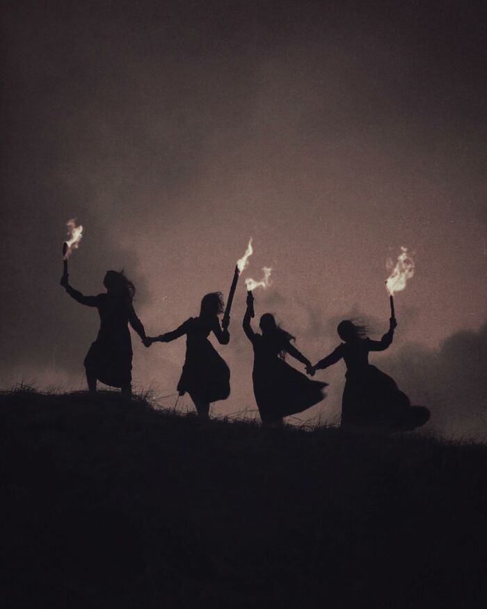 Silhouettes under a moody sky, holding torches, embodying dark escapism in Nona Limmen's photography.