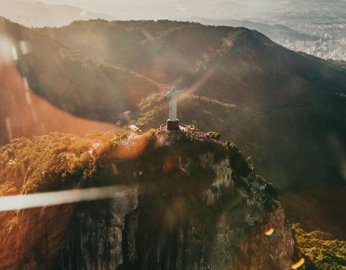 Aerial view of the Christ the Redeemer statue on a sunlit mountain ridge.