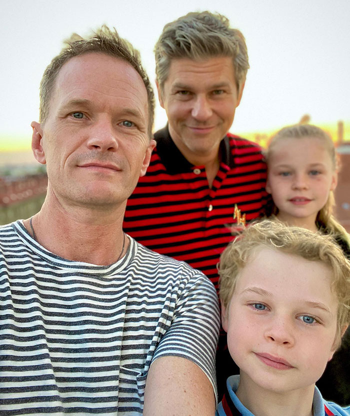 Family vacation in Fiji with kids and two adults posing for a selfie at sunset.